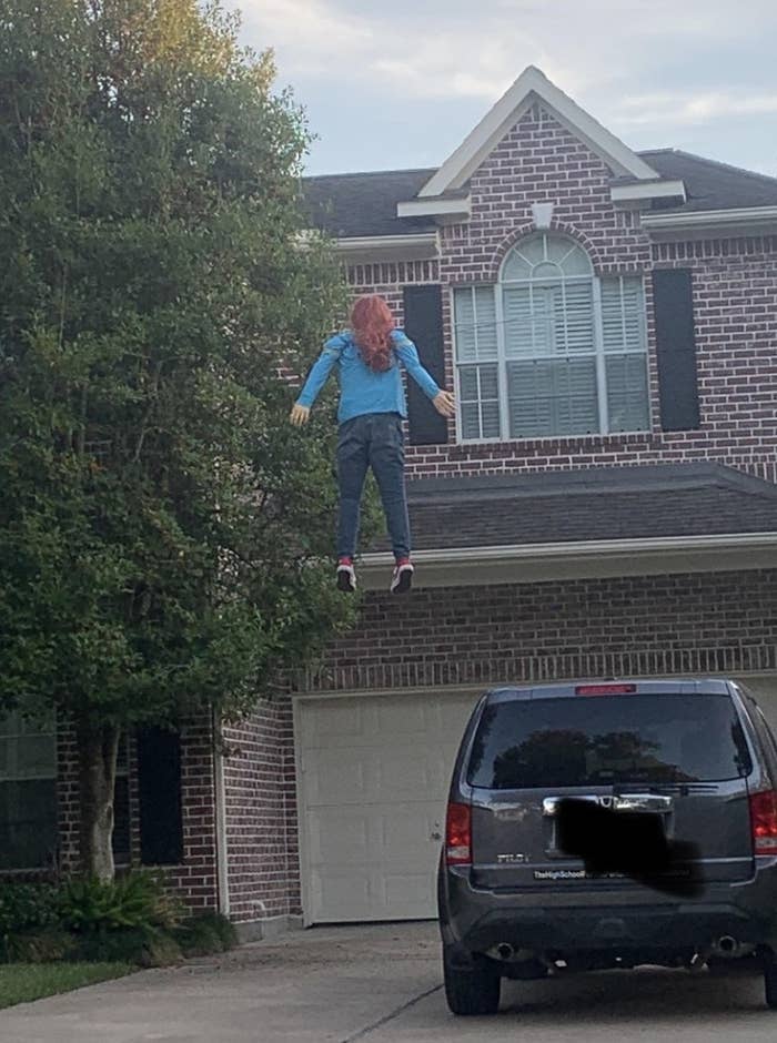 looks like a person is hanging from a telephone wire, hovering over a garage