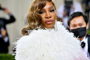 Serena Williams wears a furry white dress with chandelier earrings with her hair curled.