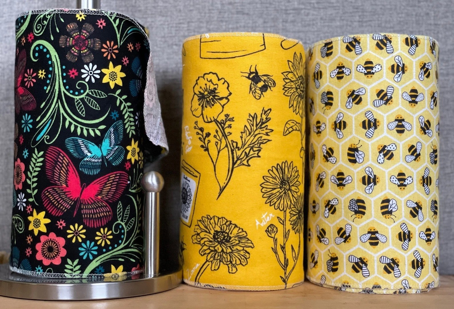 three rolls of paperless paper towels with bee and flower imagery on them