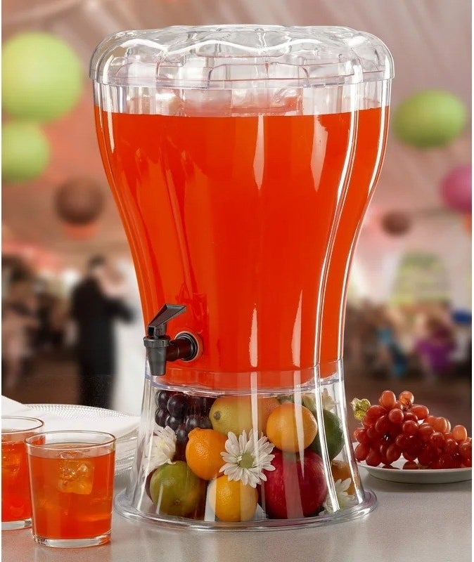 the beverage dispenser with a red drink inside and fruits underneath