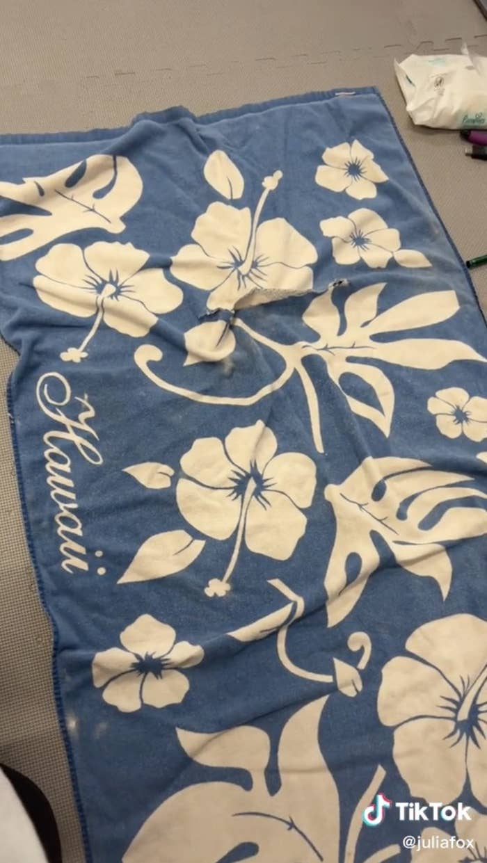 Julia shows the blue towel with white design and the word Hawaii written on the side