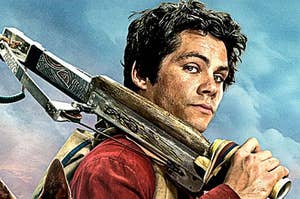 dylan obrien's character from love and monsters looks over his shoulder while holding a large knife
