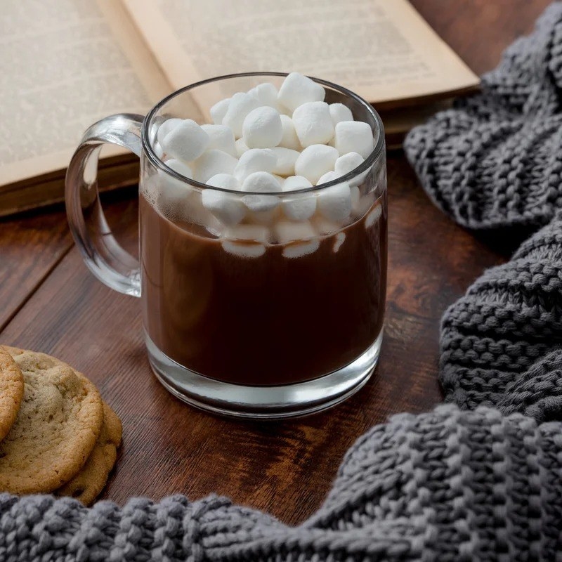 the glass mug with hot chocolate and marshmallows in it