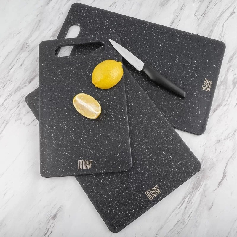 the three black speckled cutting boards with a knife and lemon