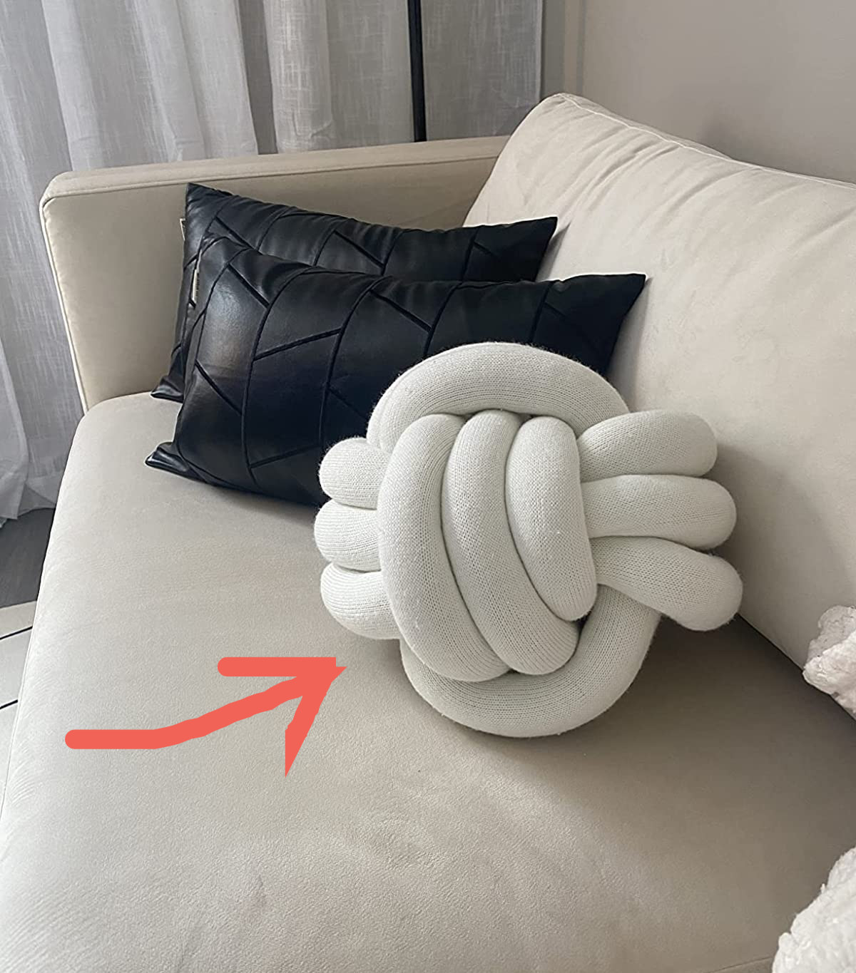 Reviewer image of white knotted pillow on a white plush couch next to two black throw pillows