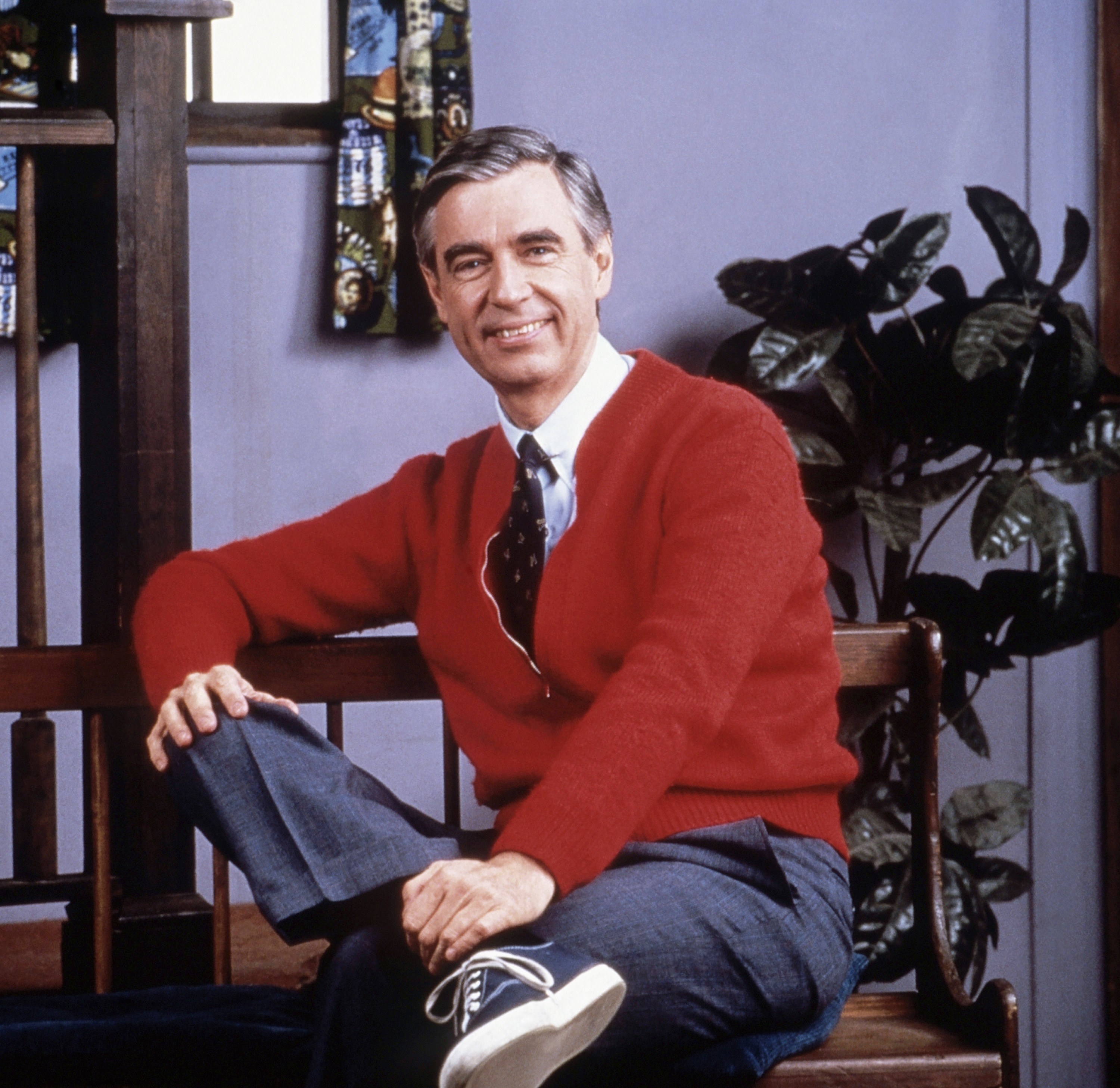 mister rogers poses on a bench