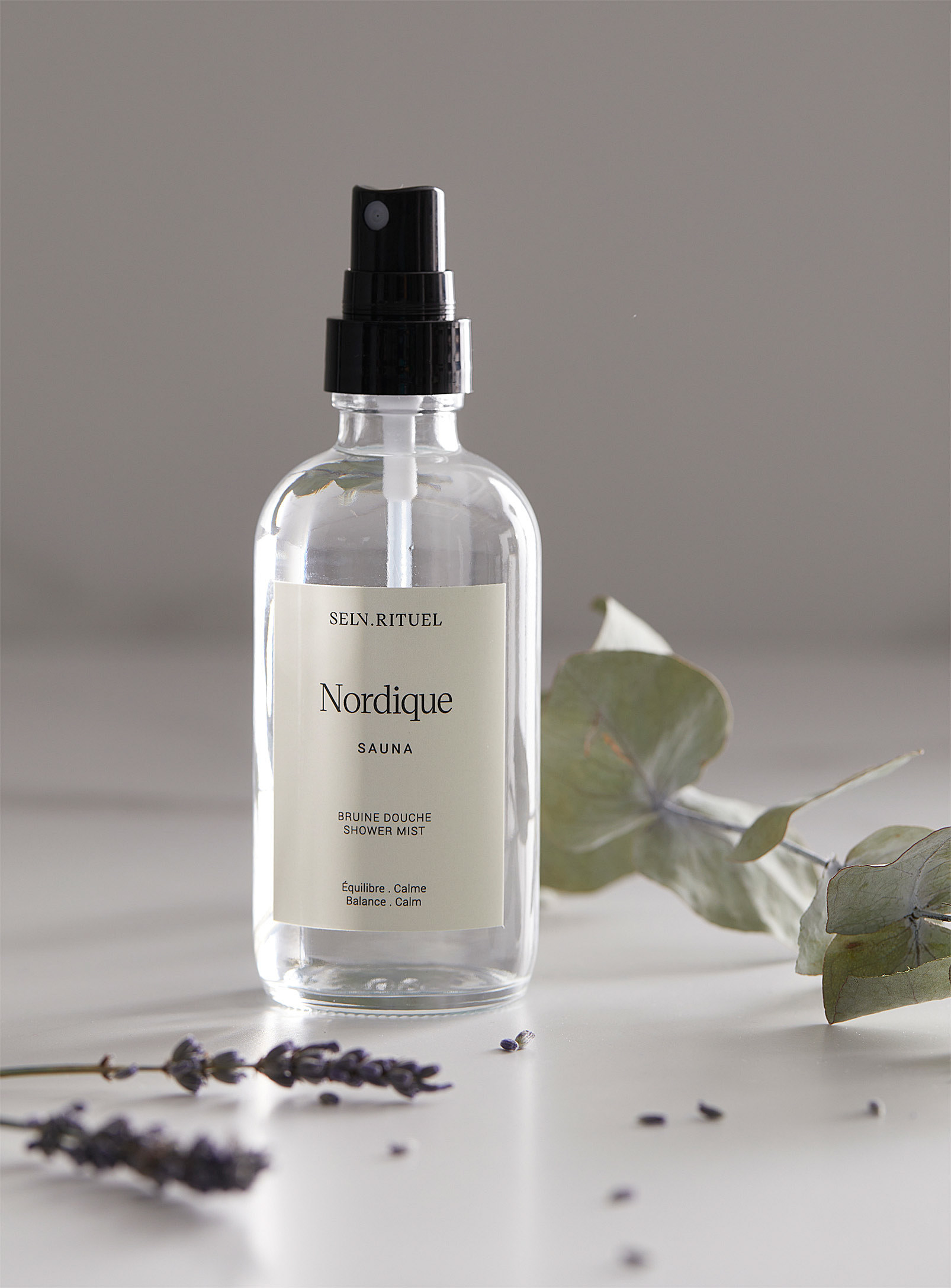 a bottle of the eucalyptus shower mist surrounded by lavender and eucalyptus branches
