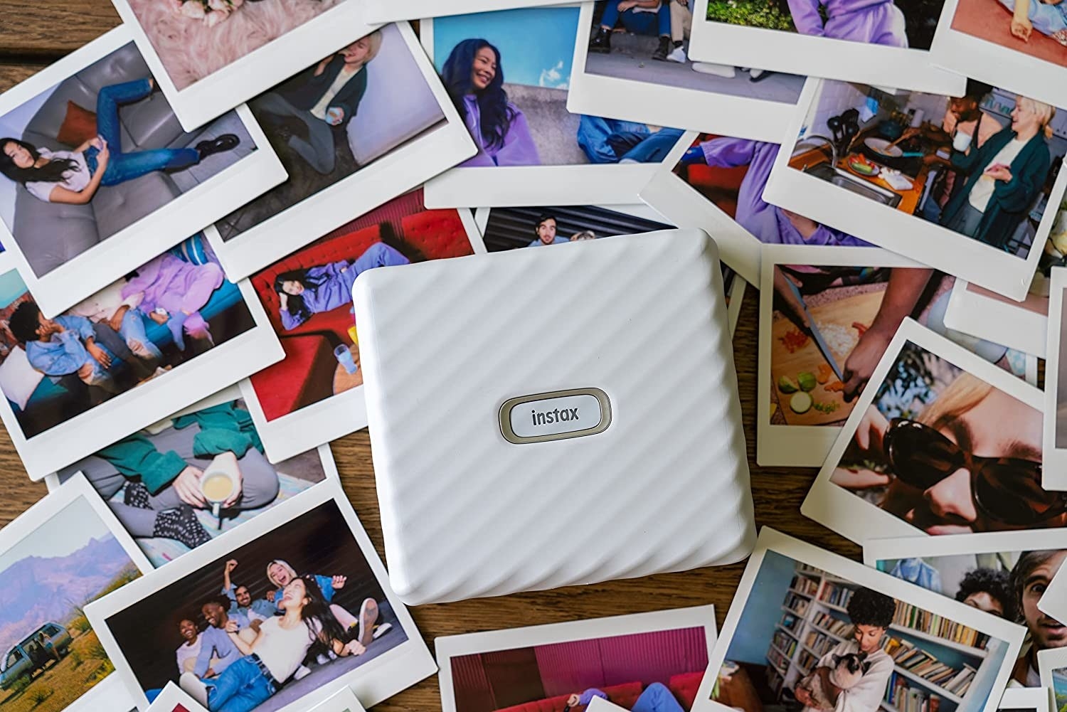 a flatlay of the square instax printer on a bed of printed photos