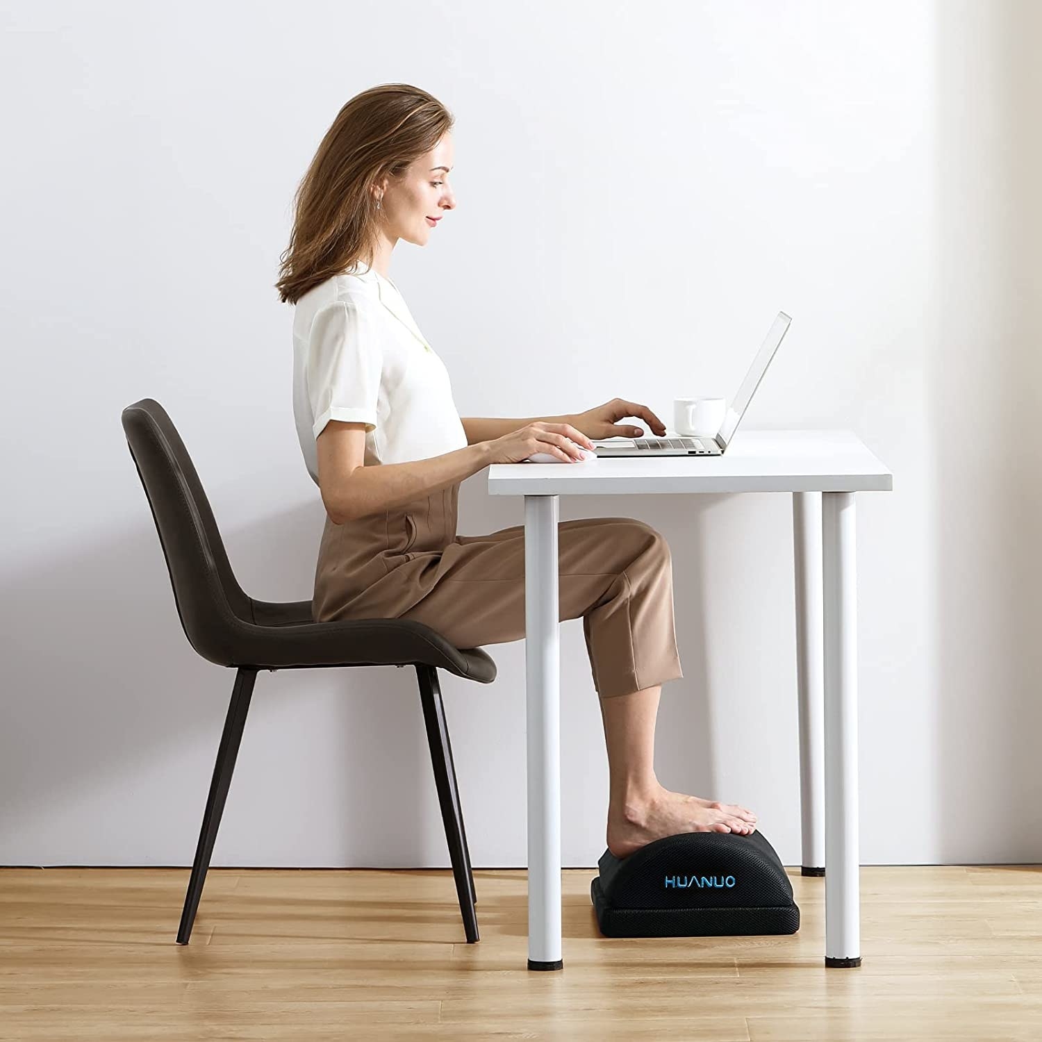 a person sitting at their desk and resting their feet on the adjustable foot rest