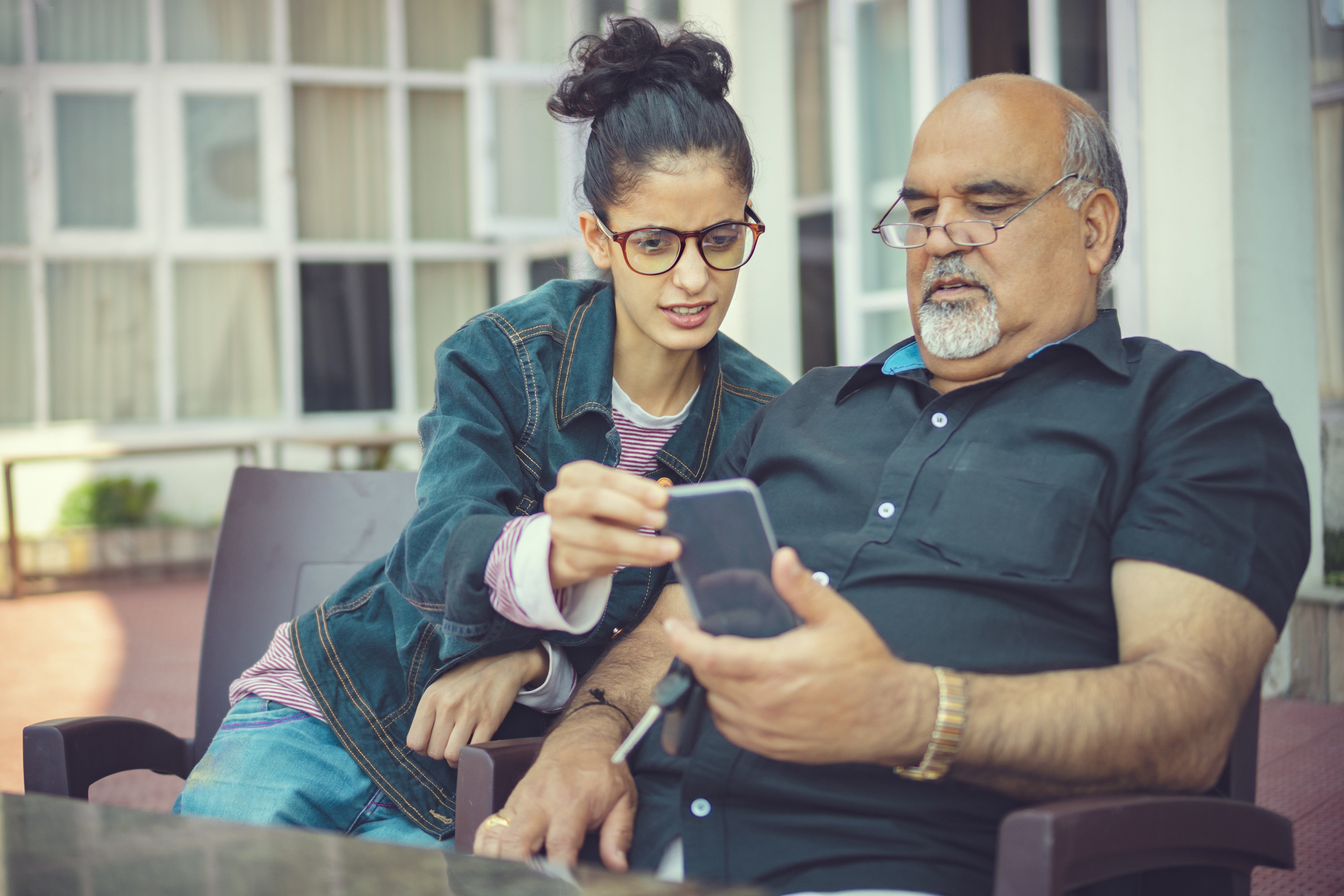 A woman and man looking at his cellphone