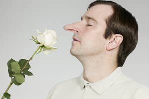A man with a long nose smells a rose