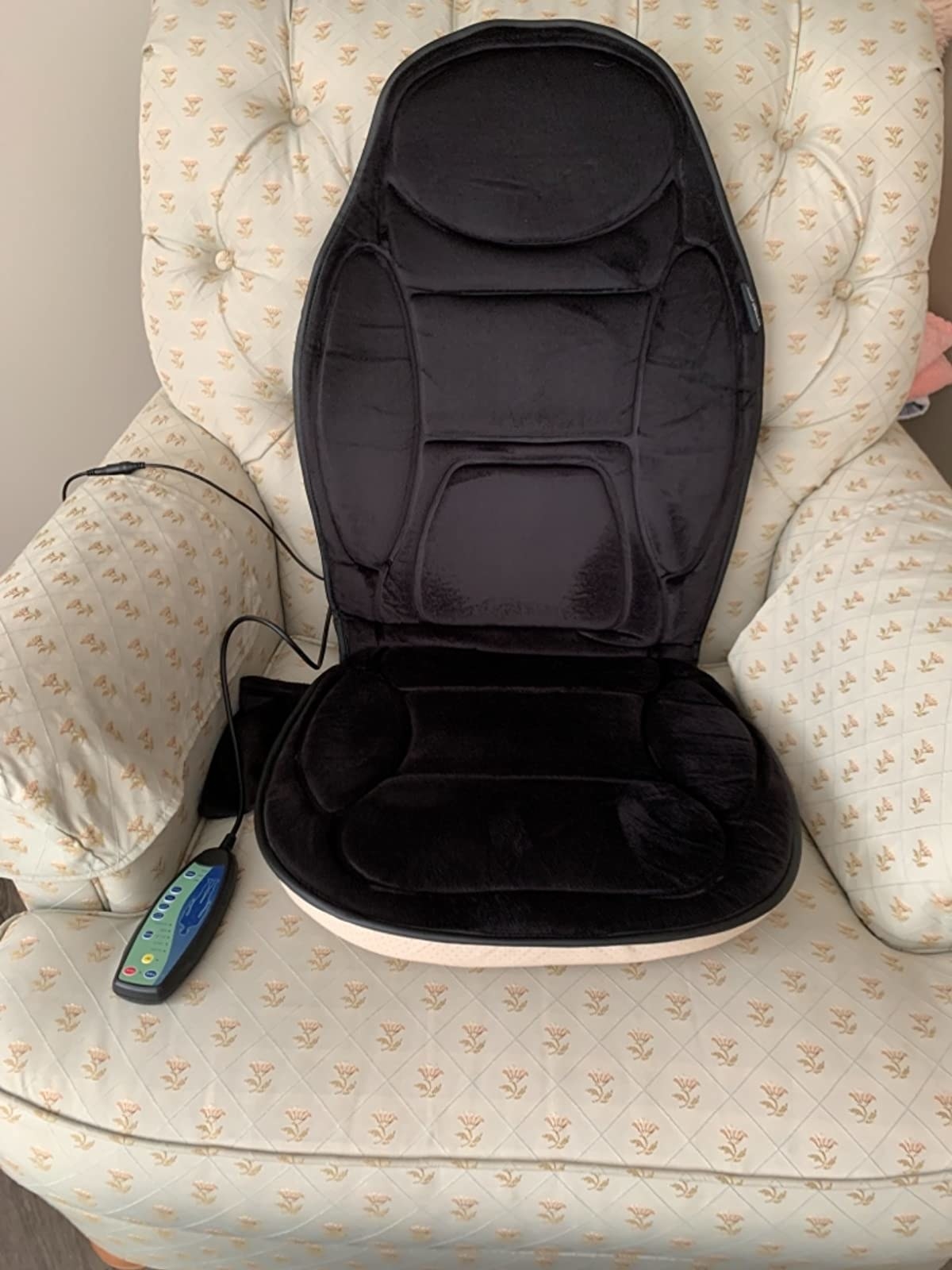 The massage seat cushion on a chair with its remote control
