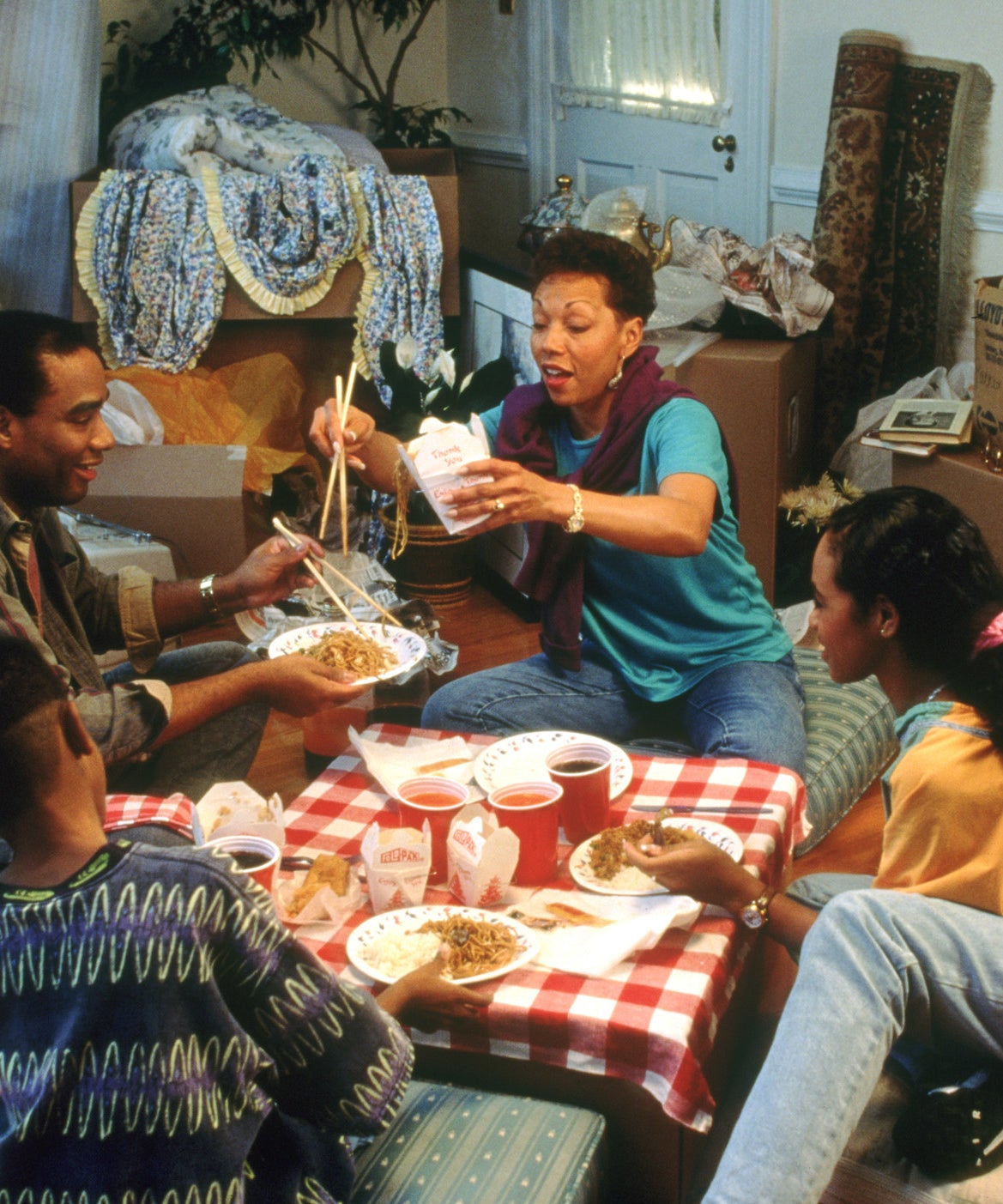 Family eats takeout dinner among open boxes in new home