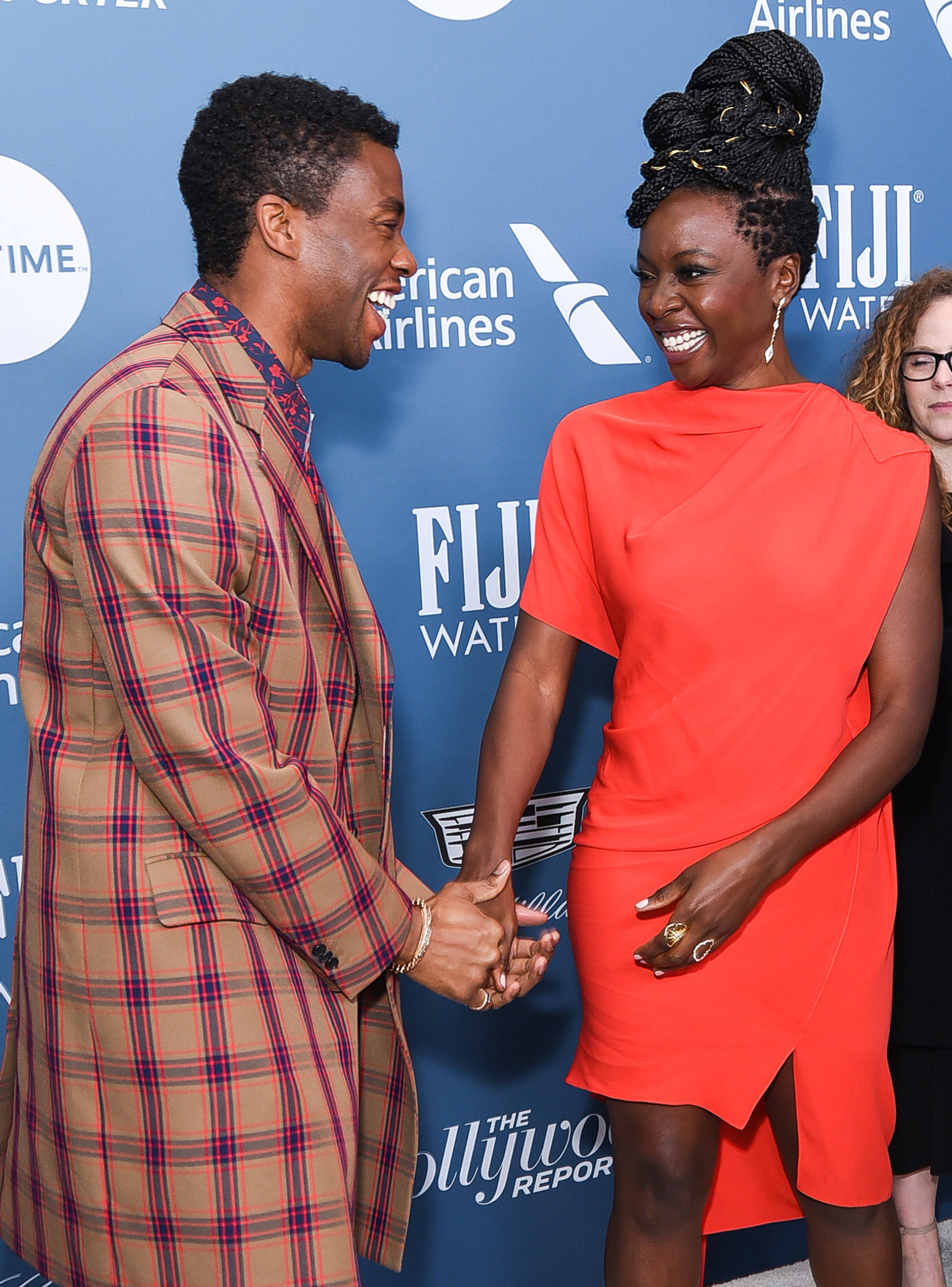 Chadwick and Danai holding hands and laughing at a red carpet event