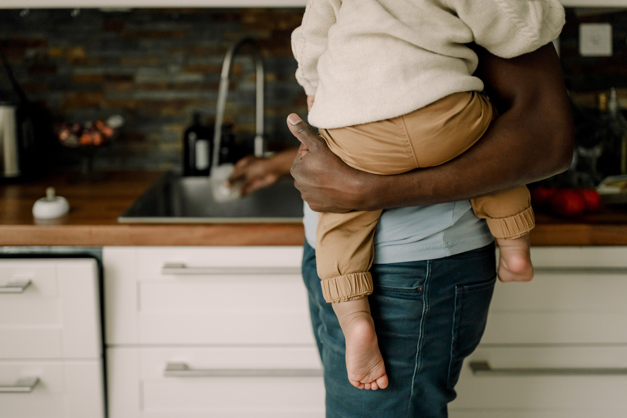 A person in a kitchen holding a baby