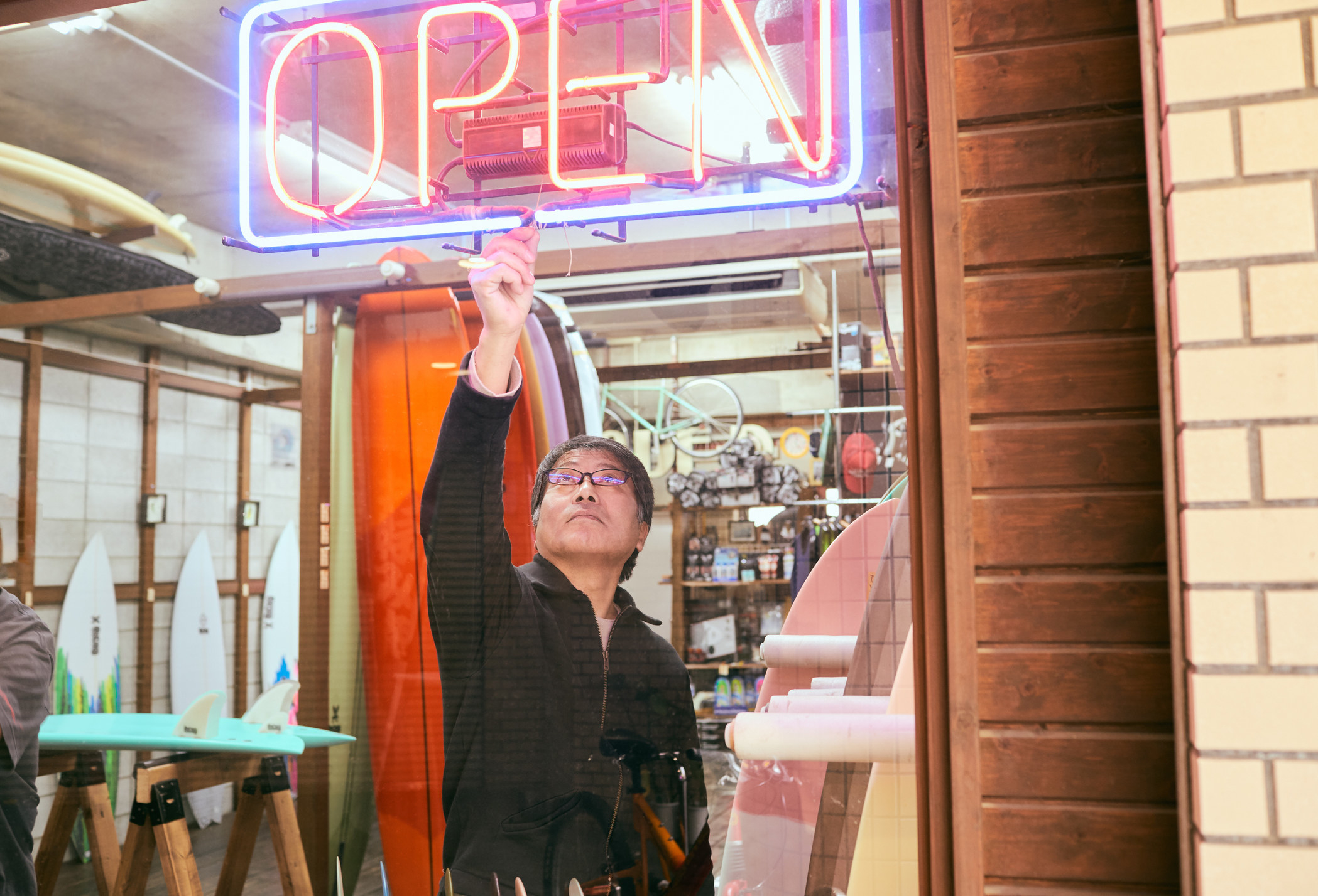Shop owner turning on an &quot;open&quot; neon sign