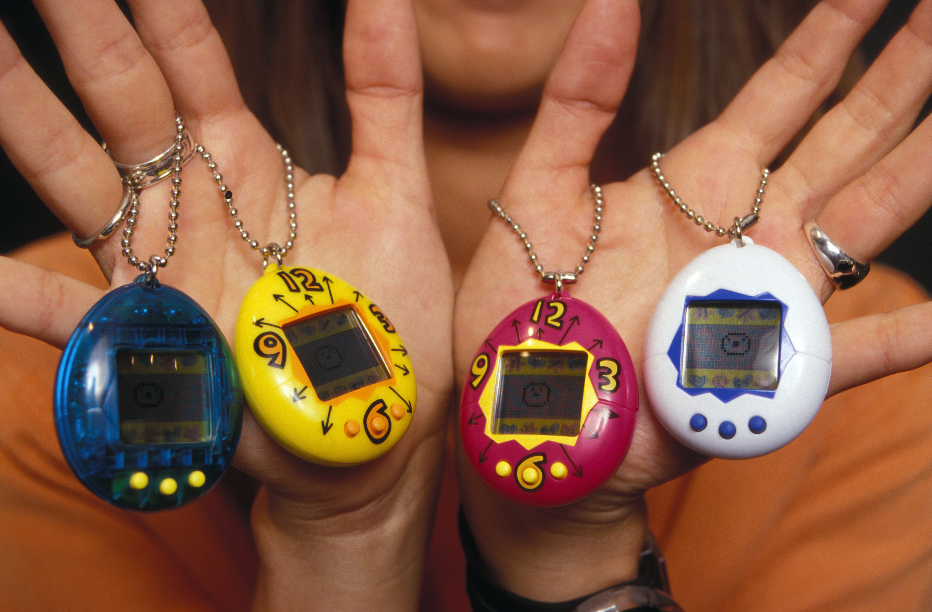 a pair of hands holding tamagotchis