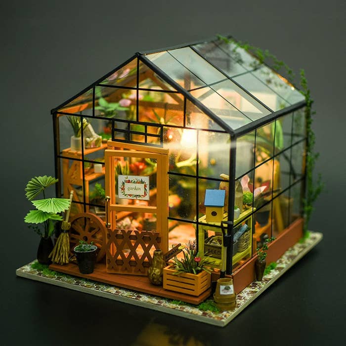 the miniature greenhouse with an LED light on inside of it
