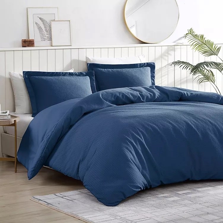 A blue comforter and pillows on a bed