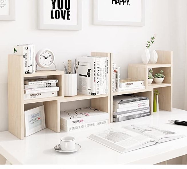 the natural white wood shelves on a desk filled with books and other items