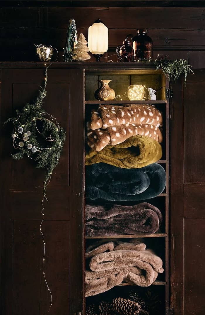 A stack of different colored blankets in a closet shelf divider