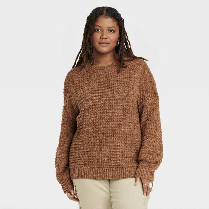 The model wears the chunky knit sweater in brown
