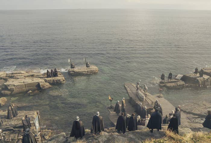 Shot from above of mourners gathered by the sea for Laena&#x27;s funeral