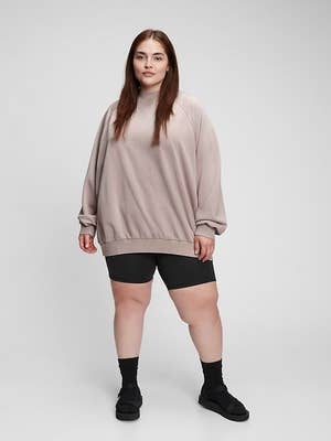model wearing a taupe sweatshirt with black shorts, socks, and sandals