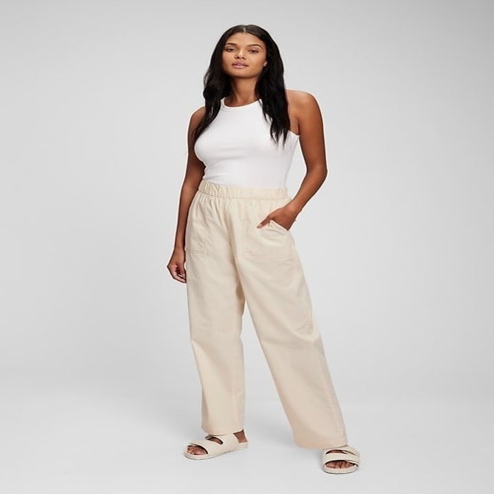 model in beige khakis with a white tank and sandals