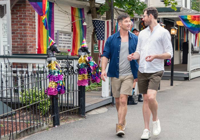 A screenshot from the movie of two men walking through a town covered in Pride flags