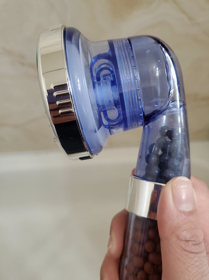 A blue showerhead in a reviewer&#x27;s hand