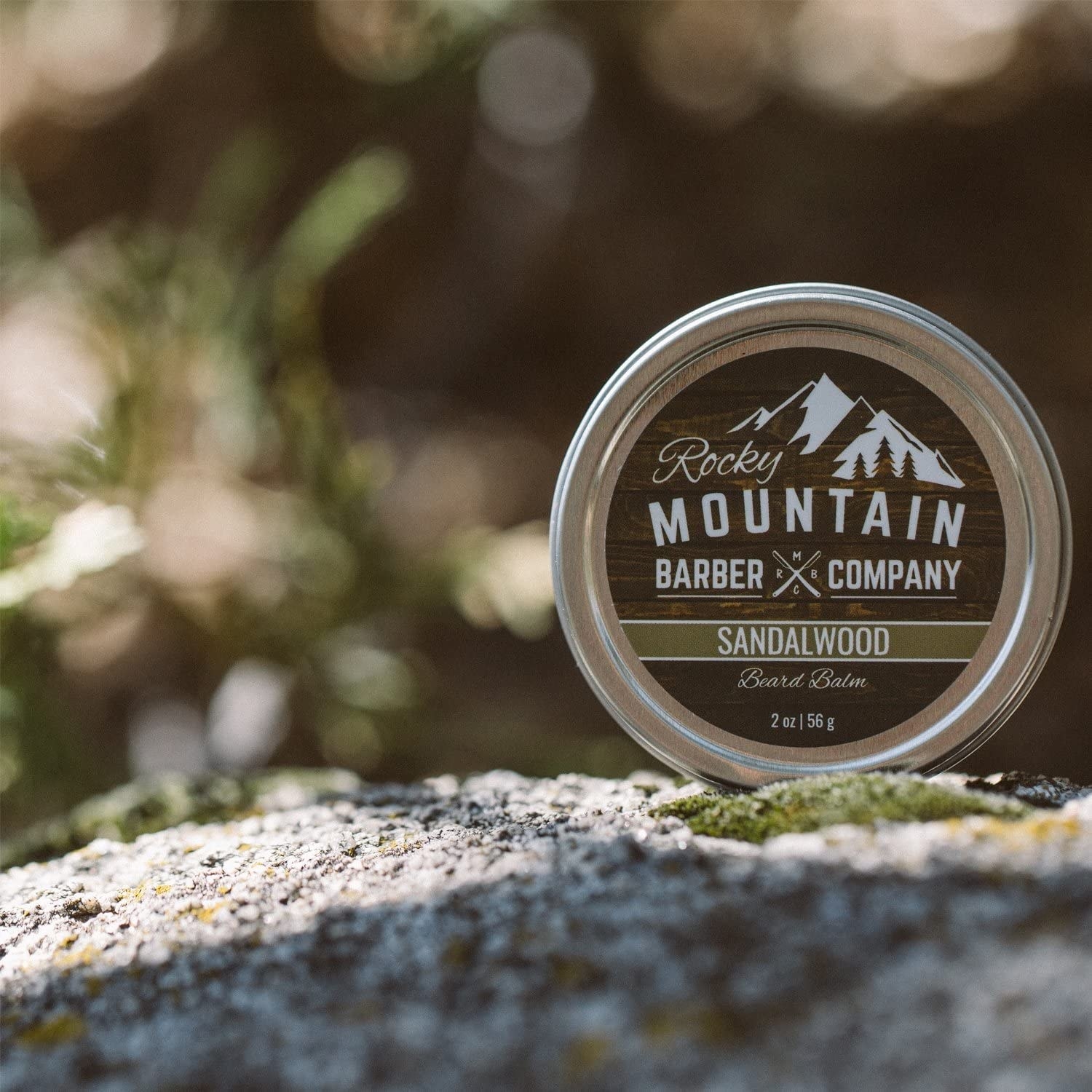 a tin of the beard balm on a mossy rock