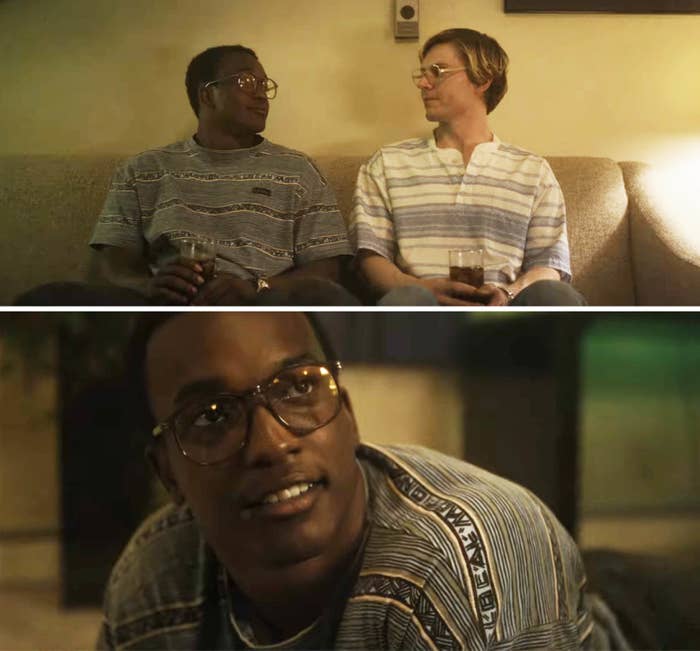 Jeffrey Dahmer in the movie, sitting on a couch and smiling at a Black man