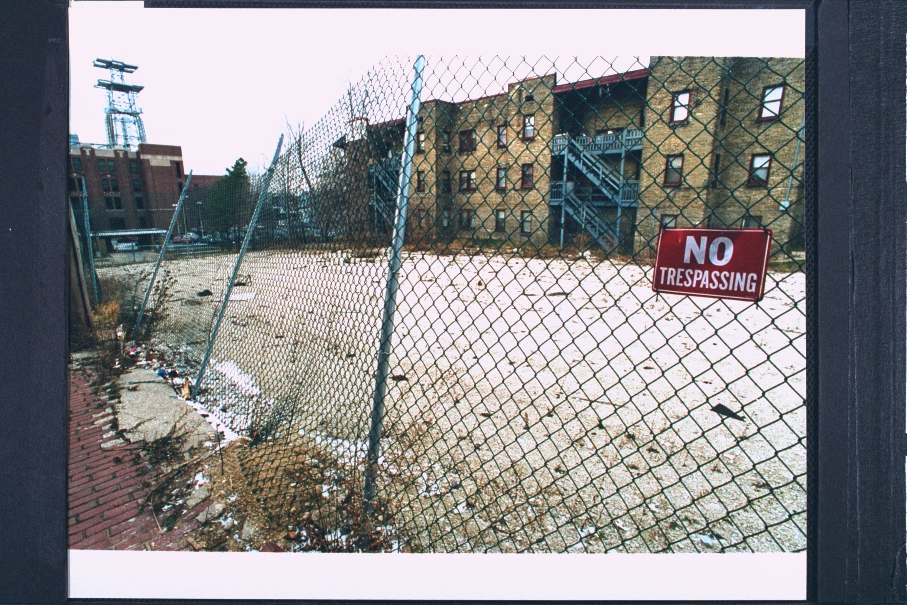 A vacant lot is surrounding by fencing with &quot;no trespassing&quot; signs