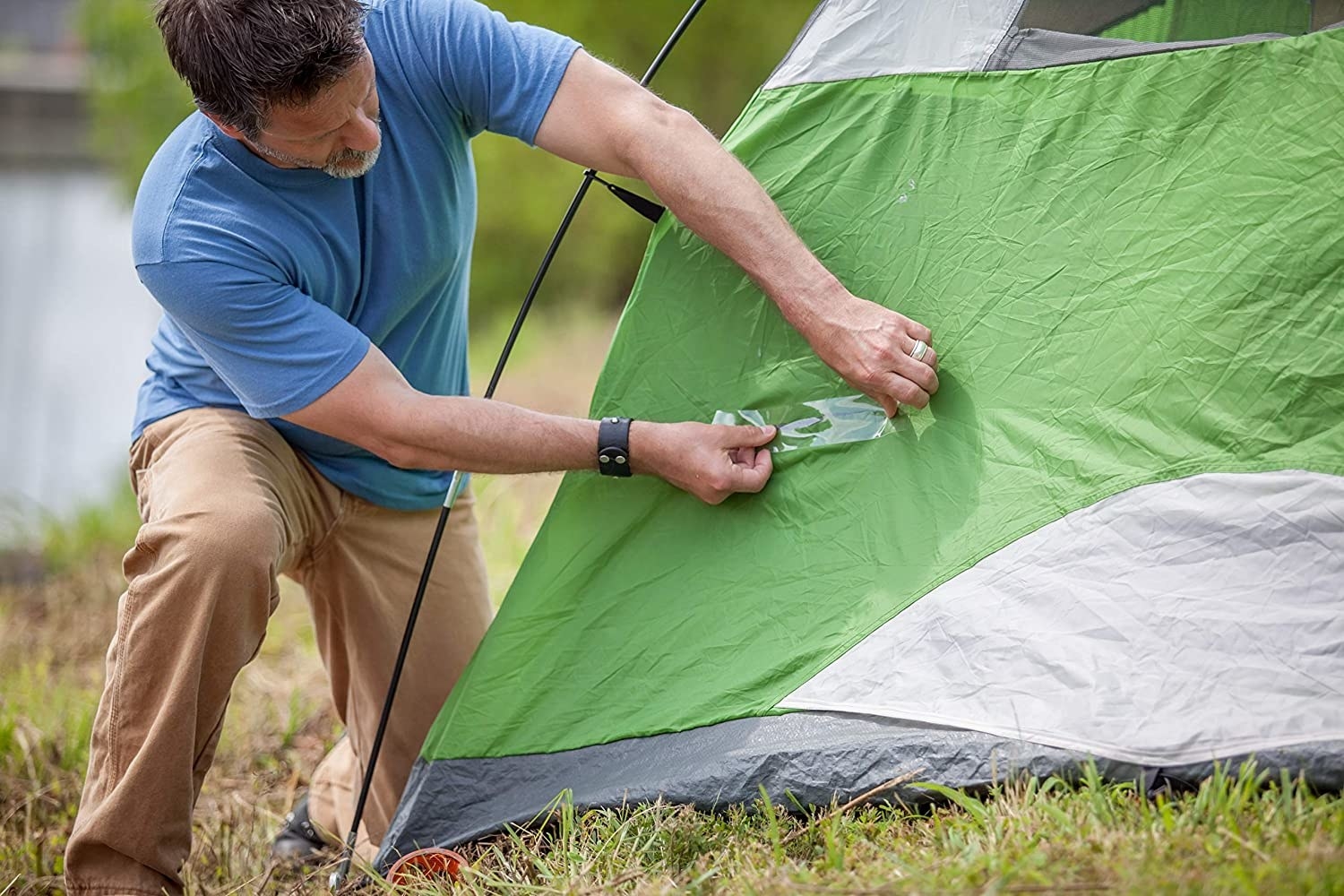 a person using the gorilla tape to seal a hole in their tent