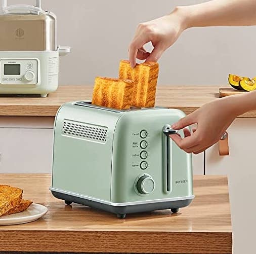 the toaster on a table with two pieces of toast popping out