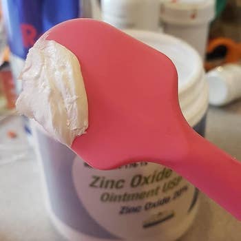 Reviewer's photo of the pink applicator over a jar of diaper cream