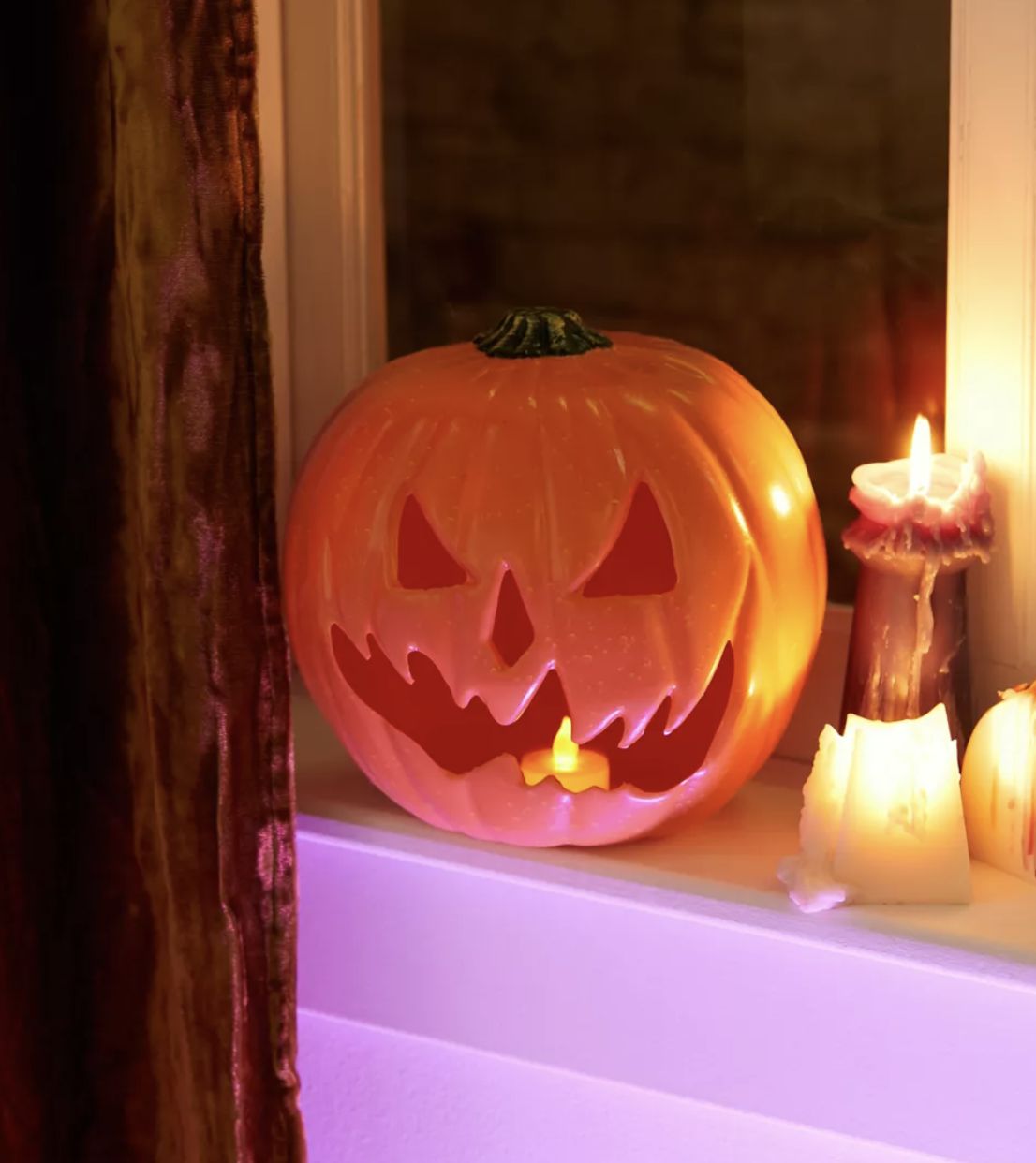 a carved pumpkin lamp on a windowsill
