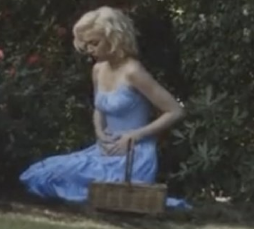 Ana as Marilyn kneeling in the grass with her hands on her stomach