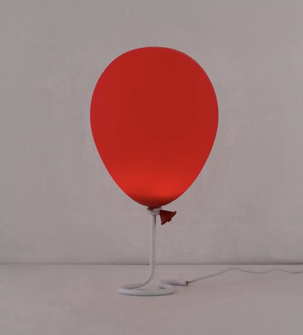 the red balloon lamp on a table in front of a plain background