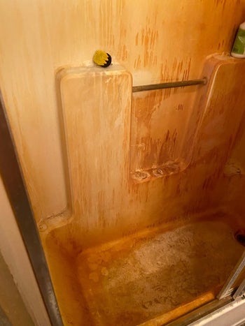 Reviewer image of orange stained tub and shower walls
