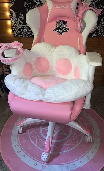 reviewer photo of a white cat paw cushion with pink pads on a pink gaming chair
