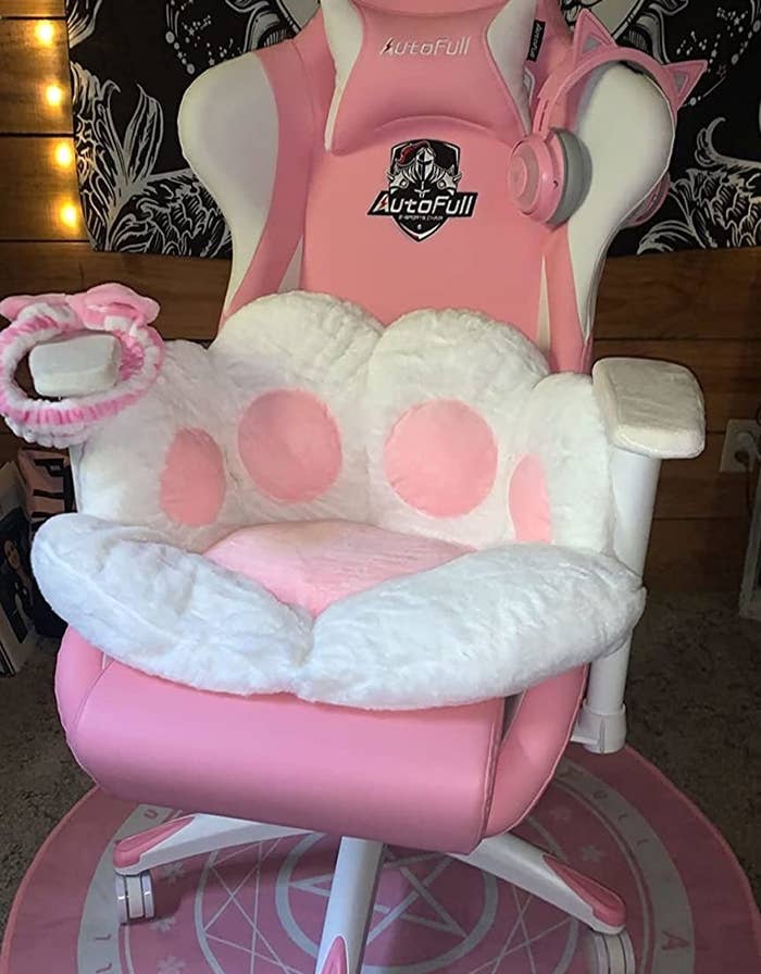 a white cat paw with pink pads on a pink gaming chair
