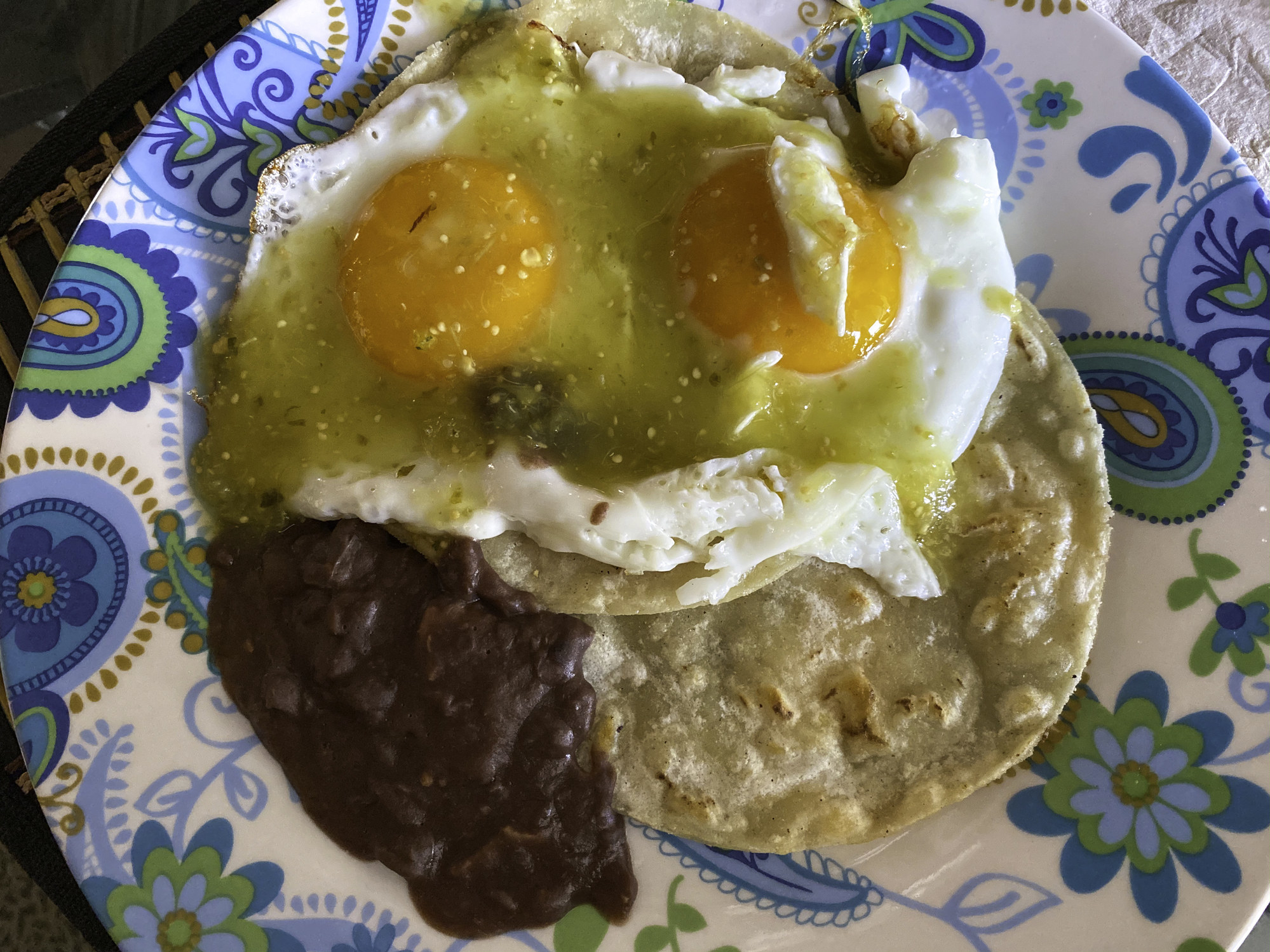 Huevos rancheros: sunny-side up eggs on a tortilla with black beans and salsa verde
