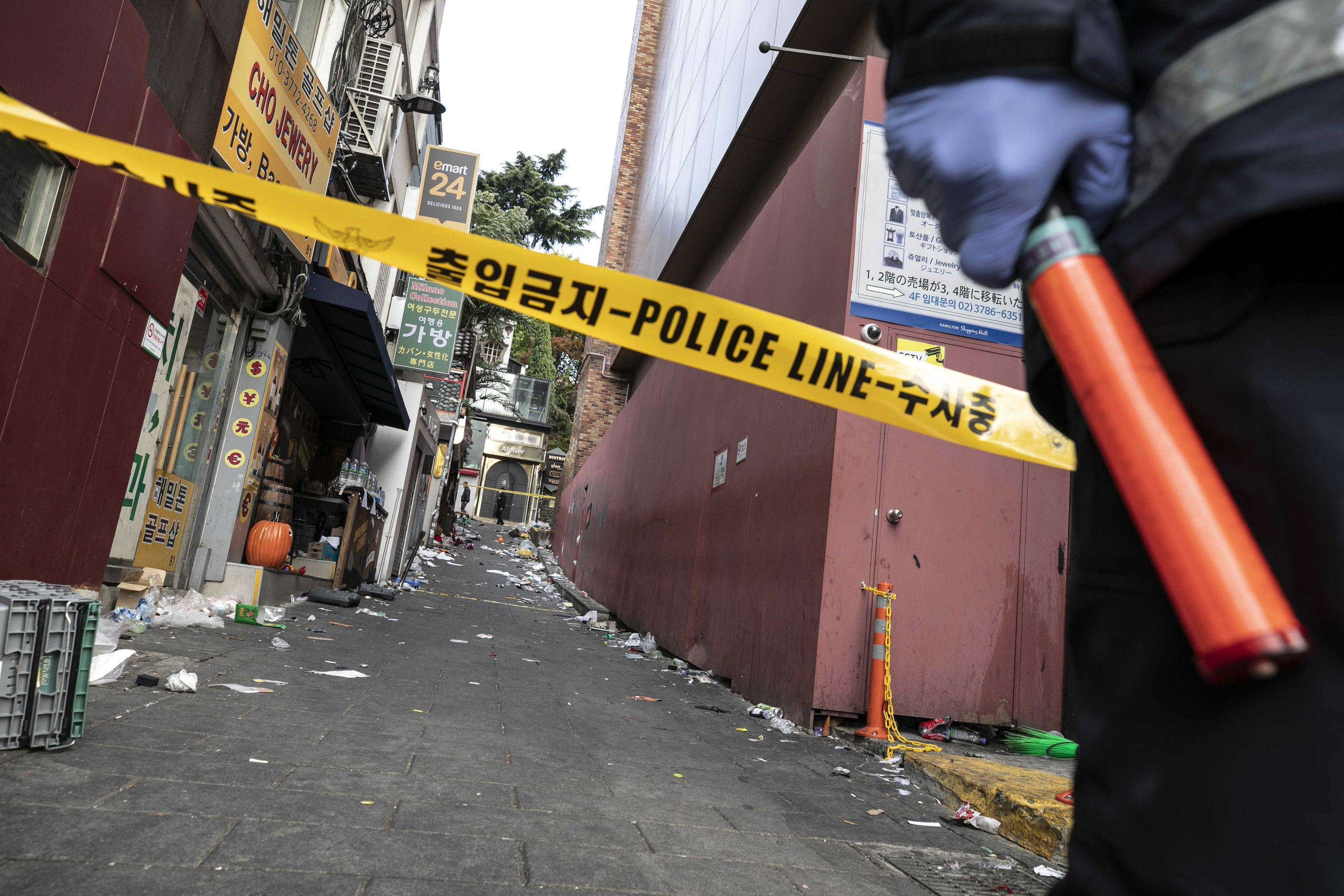 A police line across a narrow street with debris on the ground