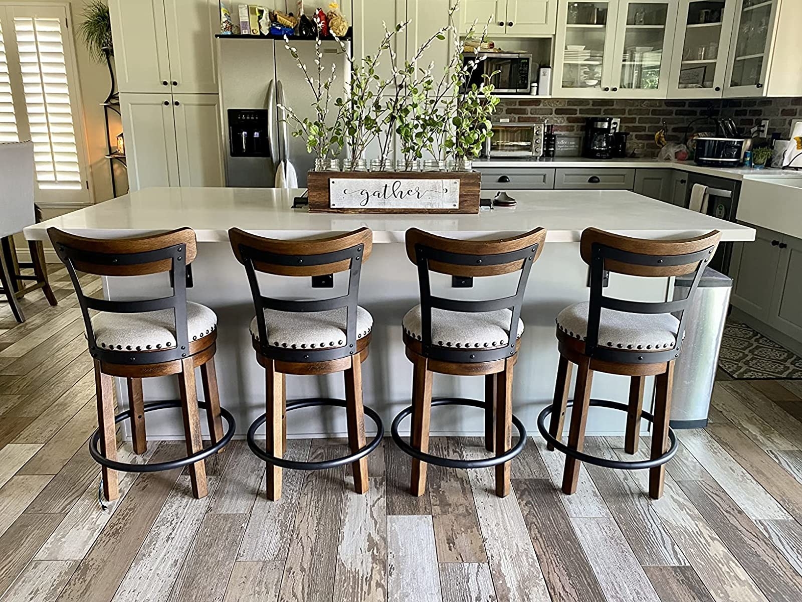 Reviewer&#x27;s photo of four of the brown and white stools at kitchen island counter