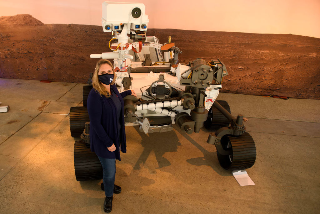 A woman standing next to a Mars rover