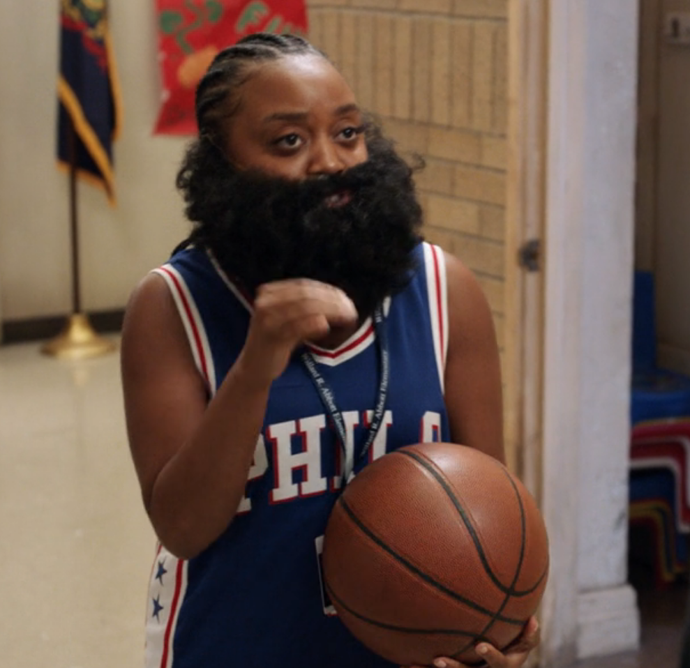 Janine wearing a basketball jersey and rocking cornrows and a full beard just like James Harden