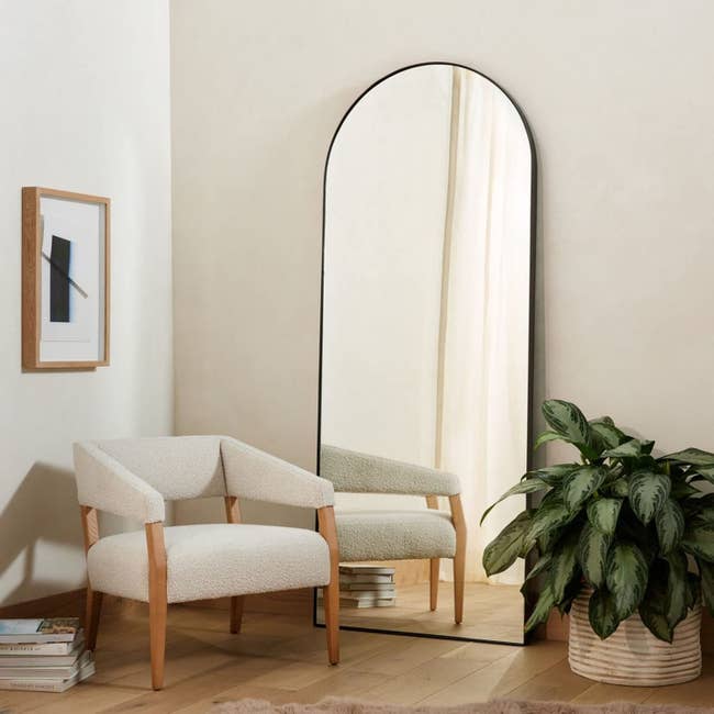 full-length black arched mirror leaning against wall