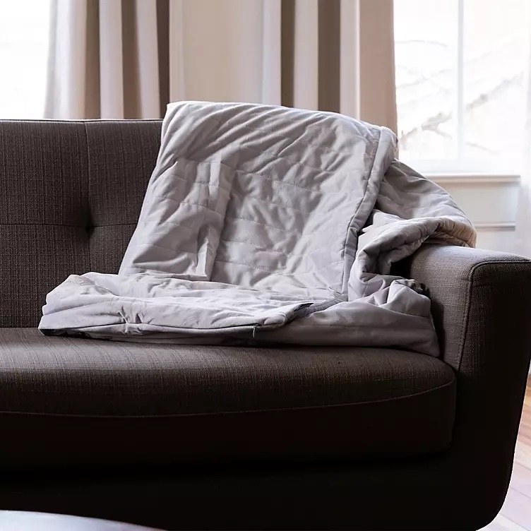 A grey blanket on a brown chair